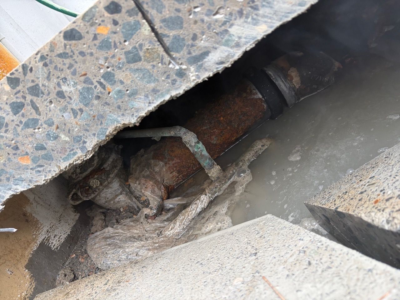 Close Up of A Damaged Pipe or Cable Under Broken Pavement — Port Macquarie Plumbing In Wauchope, NSW