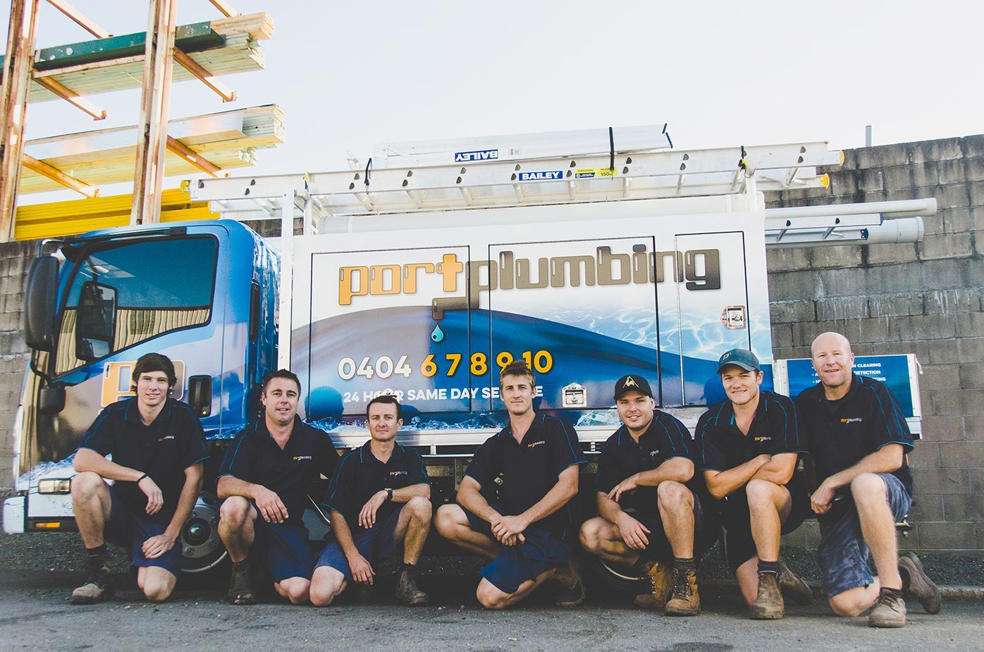 Group of Plumbers Posing in Front of A White Service Truck — Port Macquarie Plumbing In Port Macquarie, NSW
