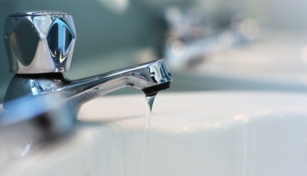 Chrome Faucet Dripping Water Into a White Sink — Port Macquarie Plumbing In Port Macquarie, NSW