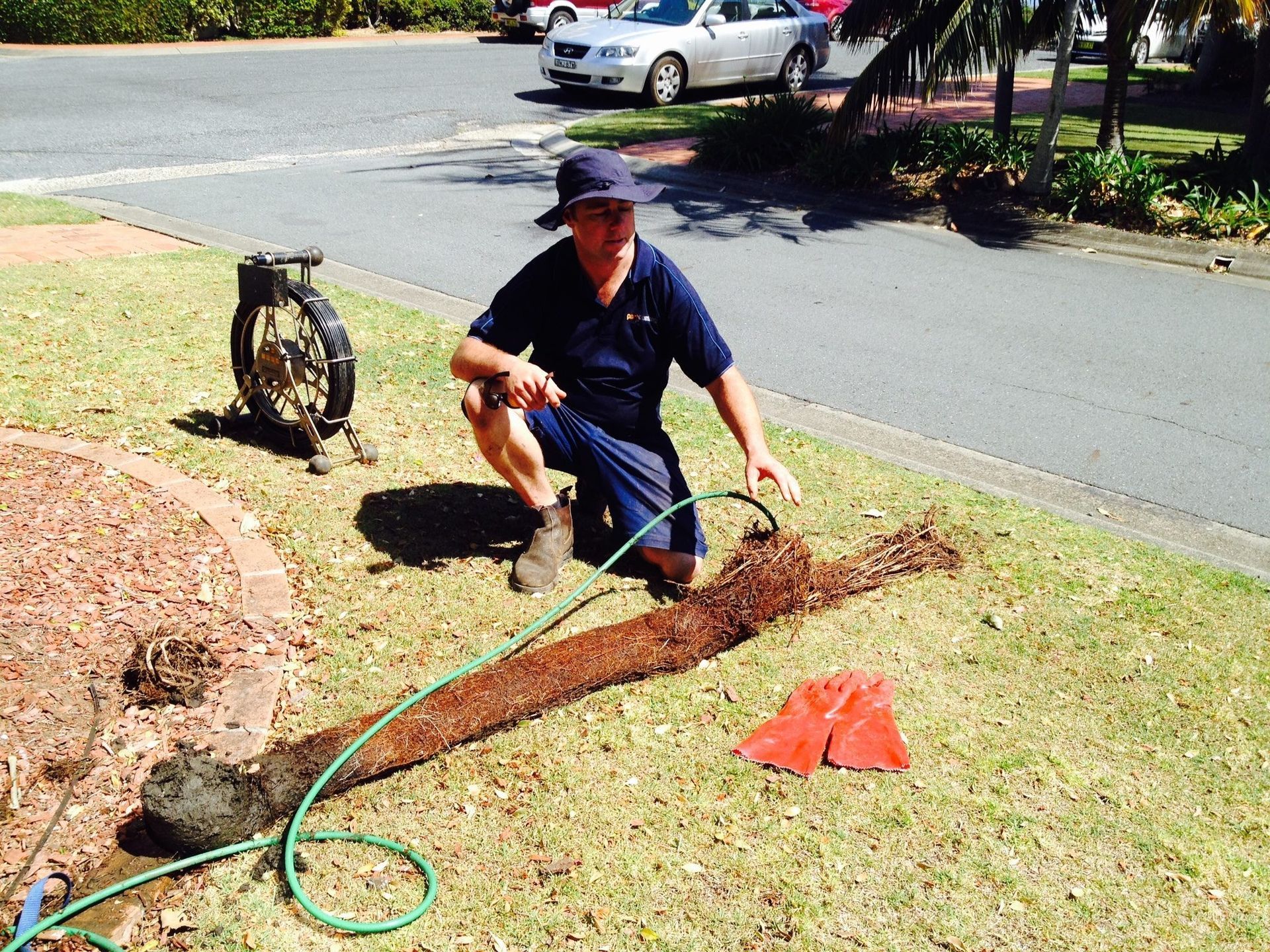 Plumber Checking Pipe in A Front Yard with A Hose — Port Macquarie Plumbing In Port Macquarie, NSW