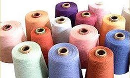 A bunch of spools of yarn of different colors are sitting on top of each other on a table.