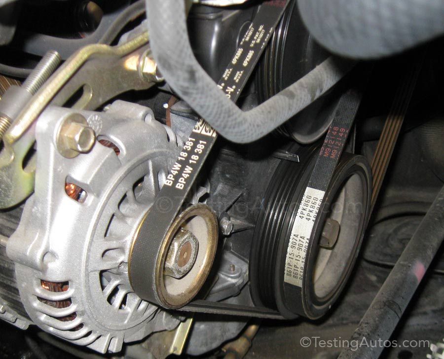 Close-up of a car alternator and serpentine belt in the engine bay.