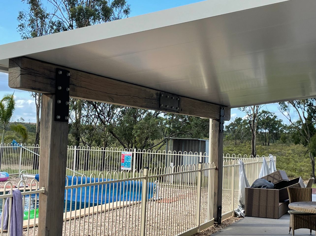 A Patio With A Covered Area And A Pool In The Background — AST Steel Constructions in Tannum Sands, QLD
