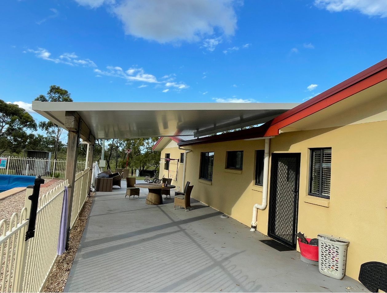 A House With A Covered Patio And A Pool In The Background — AST Steel Constructions in Tannum Sands, QLD