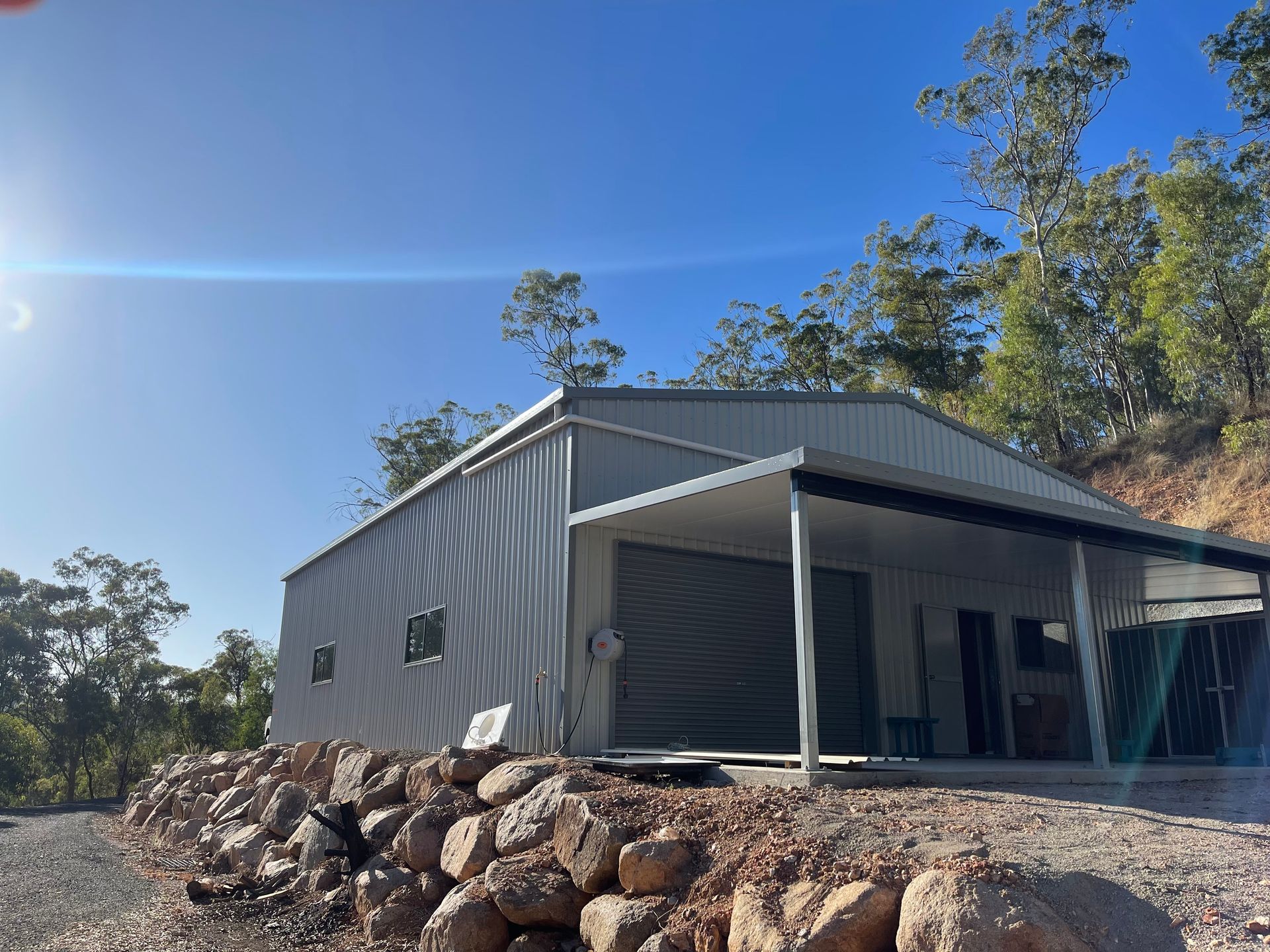 A Large Metal Building Is Sitting On Top Of A Hill Next To A Pile Of Rocks — AST Steel Constructions in Tannum Sands, QLD