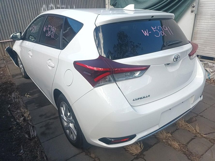 A White Toyota Corolla is Parked in Front of a Building — South West 4WD Wreckers In Brisbane, QLD