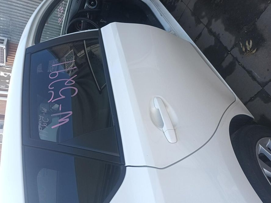 A White Car with a Black Door is Parked on the Side of the Road — South West 4WD Wreckers In Brisbane, QLD