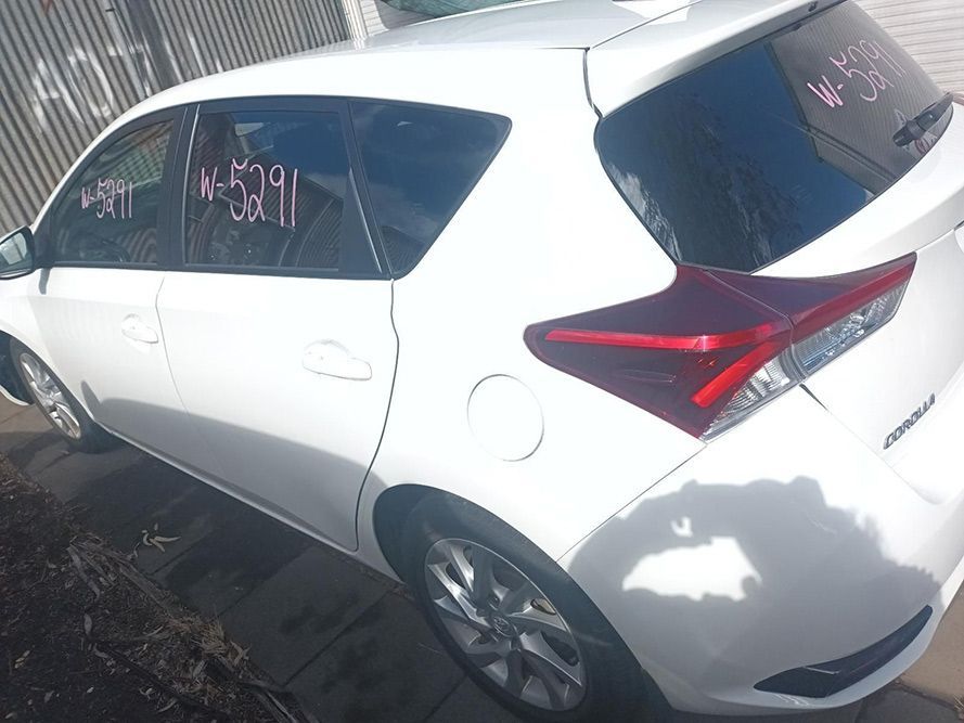 A White Car with a Red Tail Light is Parked in Front of a Fence — South West 4WD Wreckers In Brisbane, QLD