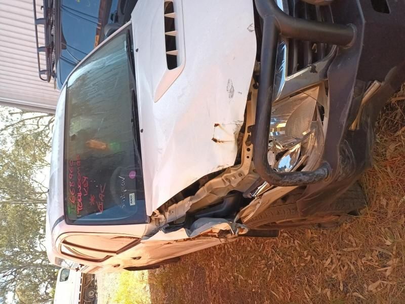 A White Truck With a Broken Hood is Parked in the Grass — South West 4WD Wreckers In Brisbane, QLD