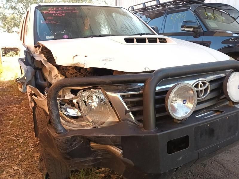A White Toyota Truck With a Damaged Front Bumper is Parked in a Field — South West 4WD Wreckers In Brisbane, QLD