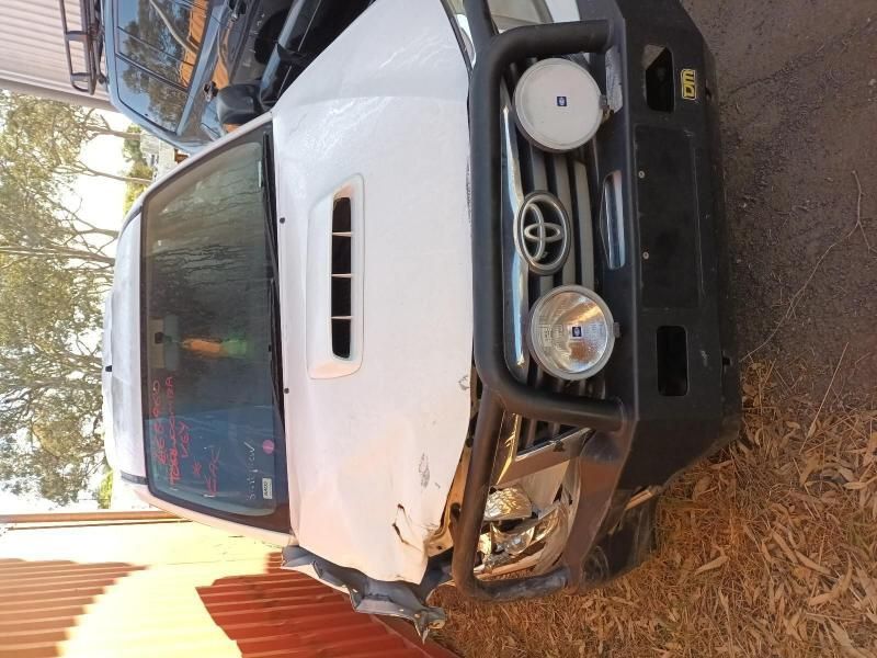 A White Toyota Truck is Parked Next to a Red Fence — South West 4WD Wreckers In Brisbane, QLD