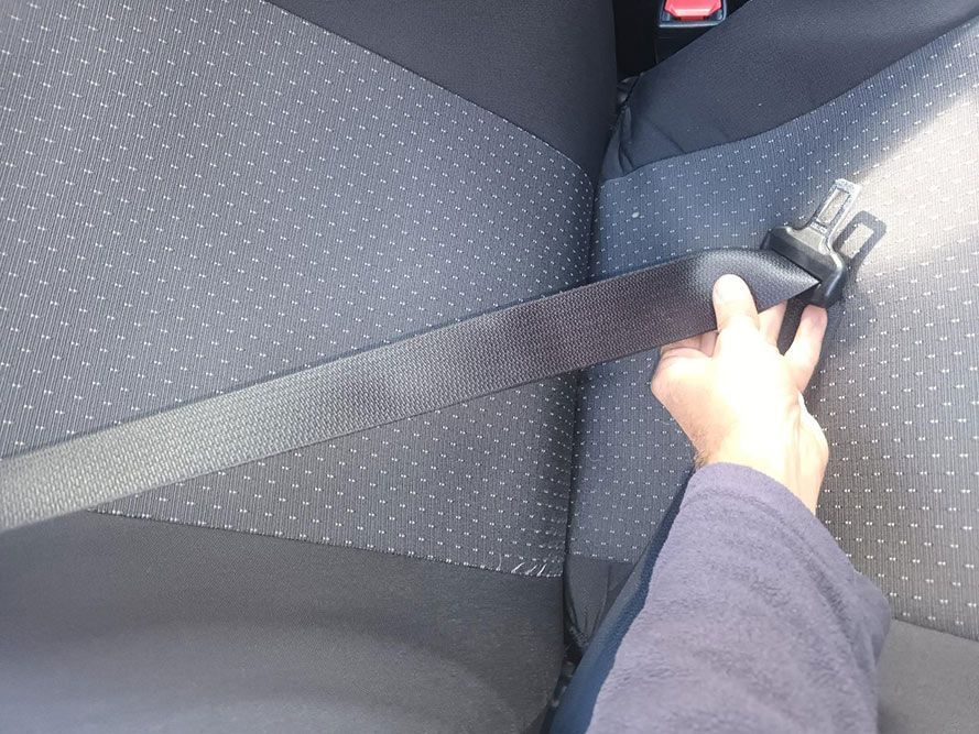 A Person is Putting on a Seat Belt in a Car — South West 4WD Wreckers In Brisbane, QLD