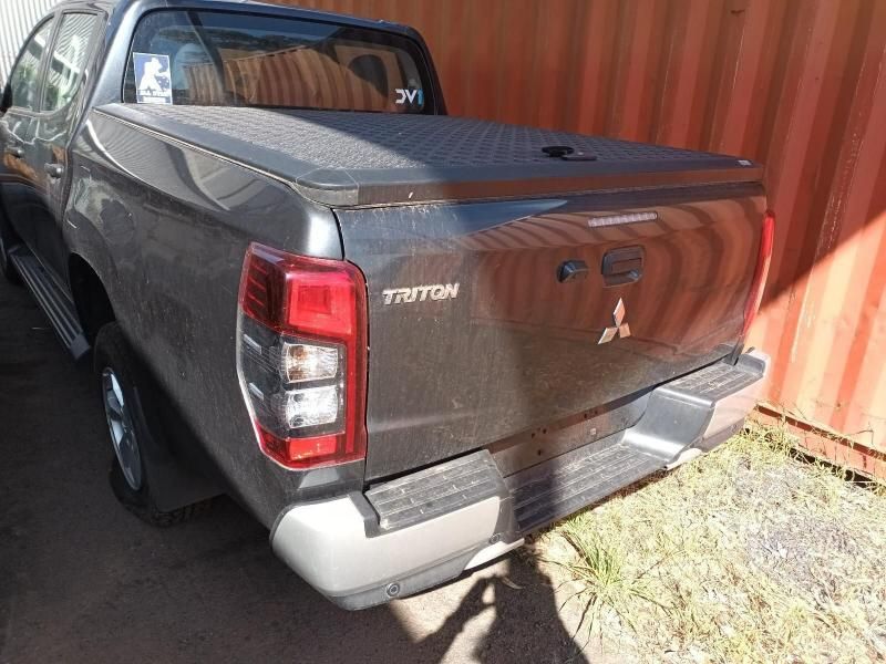 A Gray Mitsubishi Triton Truck is Parked in Front of a Red Container — South West 4WD Wreckers In Brisbane, QLD