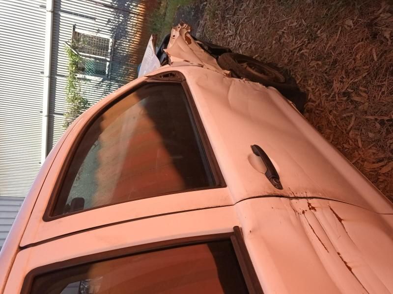 A White Car With a Broken Door is Sitting on the Ground — South West 4WD Wreckers In Brisbane, QLD