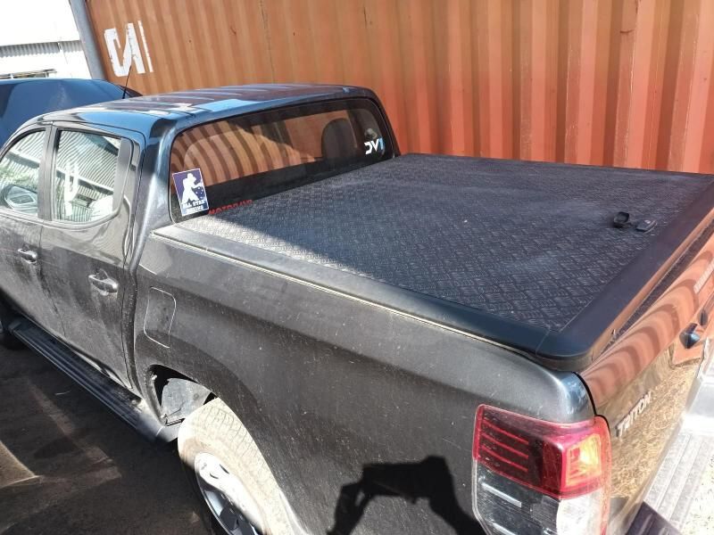 A Black Truck With a Black Bed Cover is Parked in Front of a Shipping Container — South West 4WD Wreckers In Brisbane, QLD