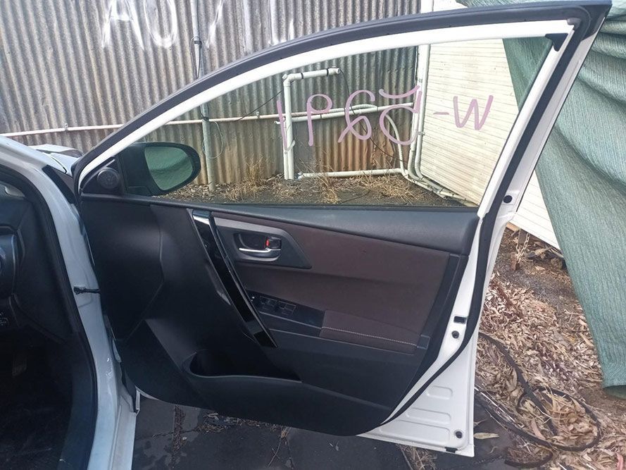 A White Car with the Door Open is Parked in Front of a Building — South West 4WD Wreckers In Brisbane, QLD