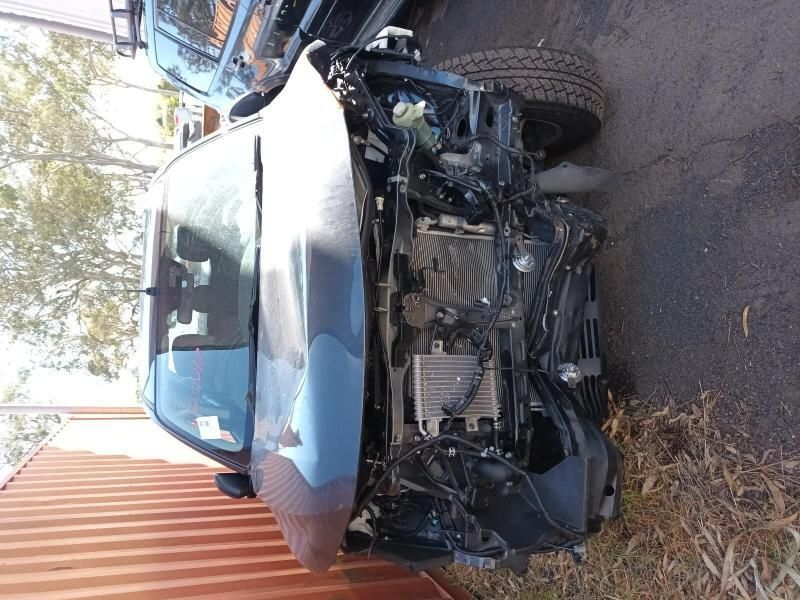 A Wrecked Car is Sitting on the Side of the Road Next to a Fence — South West 4WD Wreckers In Brisbane, QLD