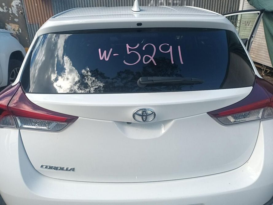 A White Toyota Corolla is Parked in Front of a Building — South West 4WD Wreckers In Brisbane, QLD