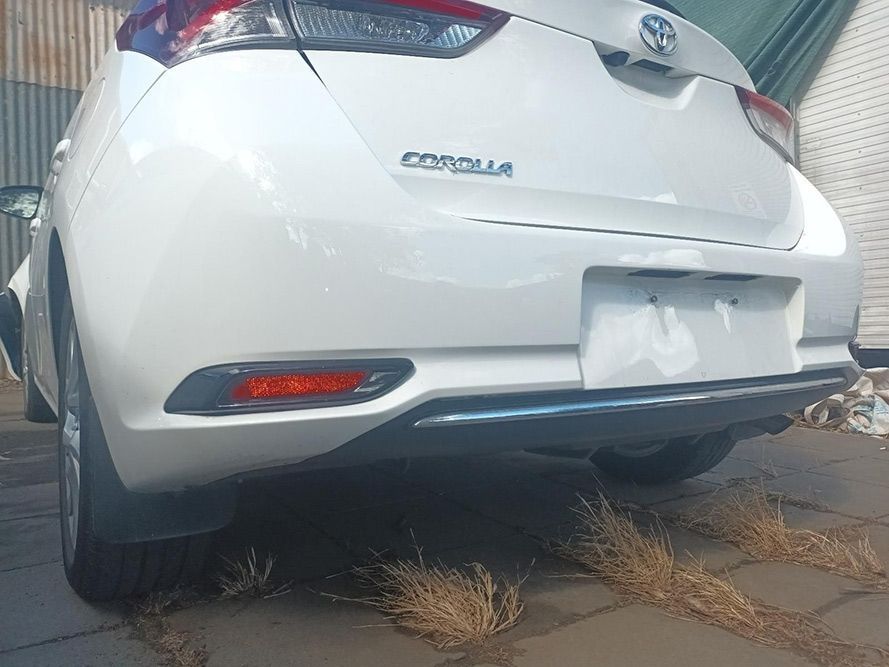 A White Toyota Corolla is Parked on a Sidewalk in Front of a Building — South West 4WD Wreckers In Brisbane, QLD