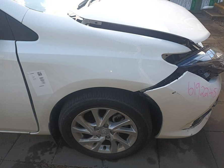 A White Car with a Damaged Front Bumper is Parked on the Side of the Road — South West 4WD Wreckers In Brisbane, QLD