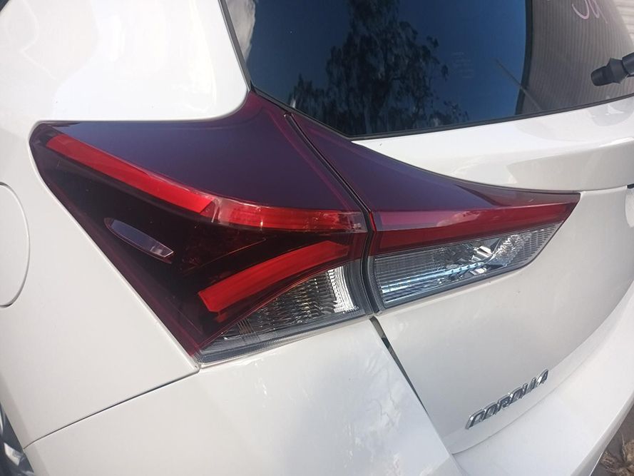 A White Car with a Red Tail Light is Parked on the Side of the Road — South West 4WD Wreckers In Brisbane, QLD