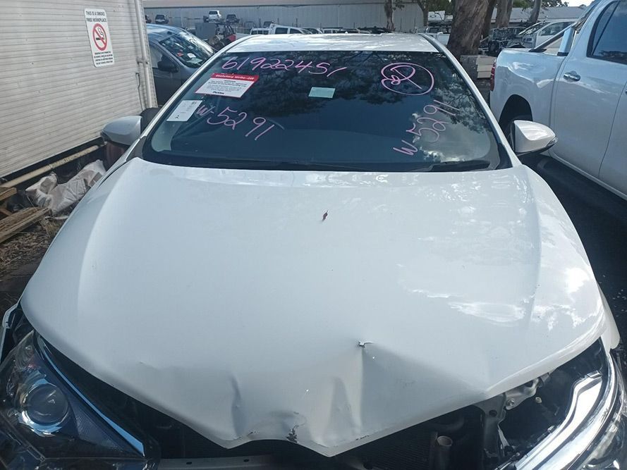 A White Car with a Damaged Hood is Parked in a Parking Lot — South West 4WD Wreckers In Brisbane, QLD