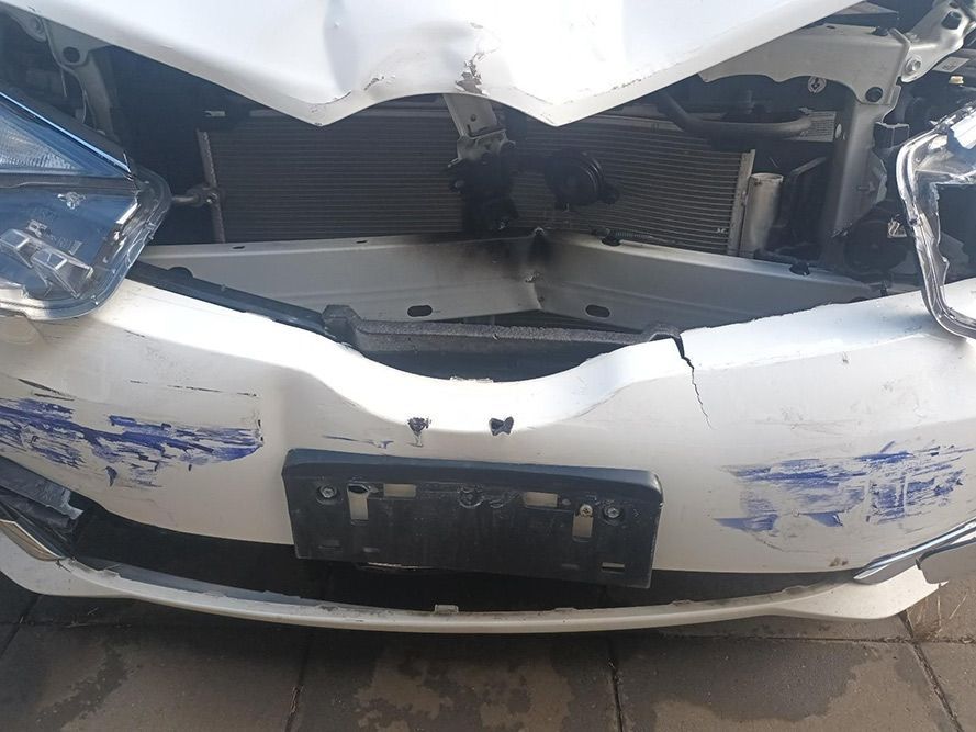A White Car with a Damaged Front Bumper is Parked on a Sidewalk — South West 4WD Wreckers In Brisbane, QLD