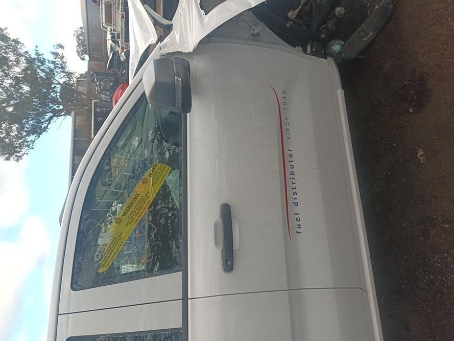 A White Van with a Yellow Sticker on the Door is Sitting on the Ground — South West 4WD Wreckers In Brisbane, QLD