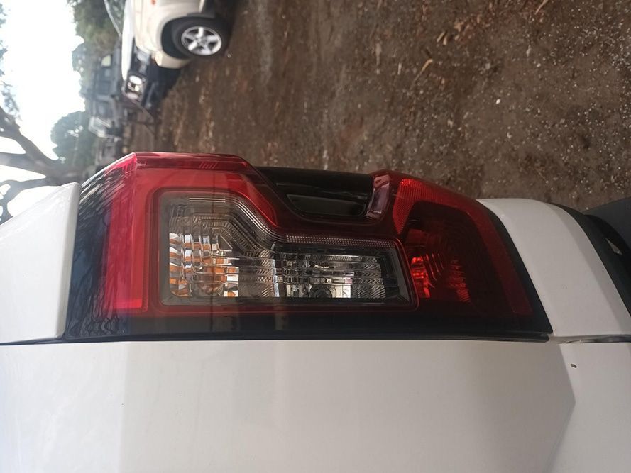 A White Truck with a Red Tail Light is Parked in a Dirt Lot — South West 4WD Wreckers In Brisbane, QLD