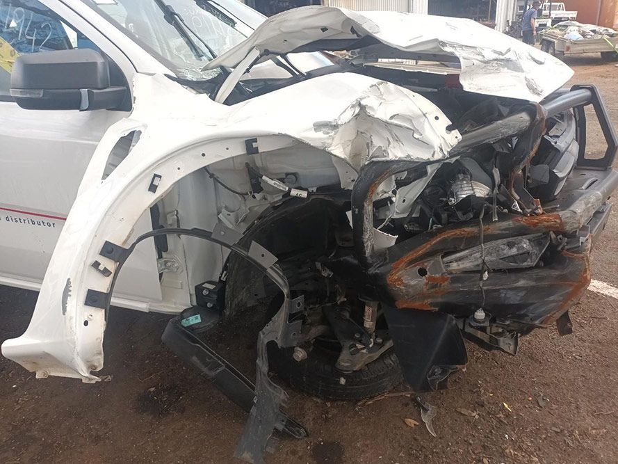 A White Car with a Damaged Front End is Parked on the Side of the Road — South West 4WD Wreckers In Brisbane, QLD