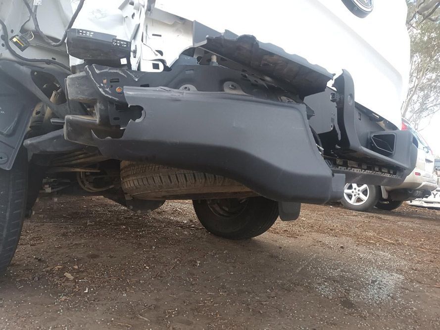 A White Truck with a Broken Bumper is Parked in a Dirt Lot — South West 4WD Wreckers In Brisbane, QLD