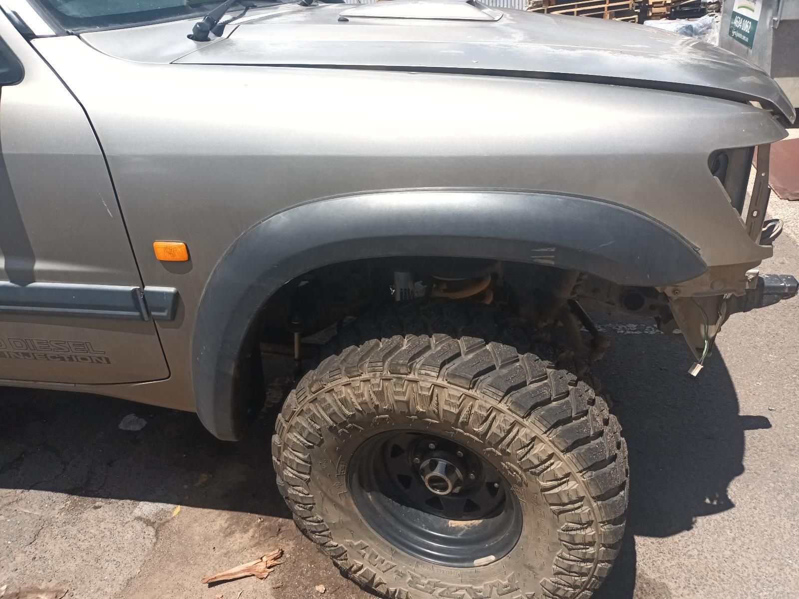 A Silver Truck with a Large Tire is Parked on the Side of the Road — South West 4WD Wreckers In Brisbane, QLD