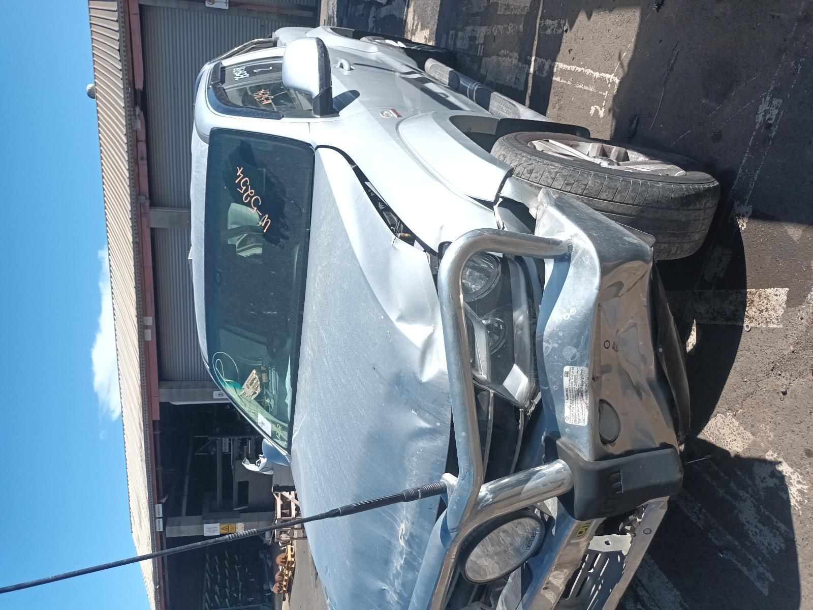 A Damaged Car is Parked in Front of a Garage — South West 4WD Wreckers In Brisbane, QLD