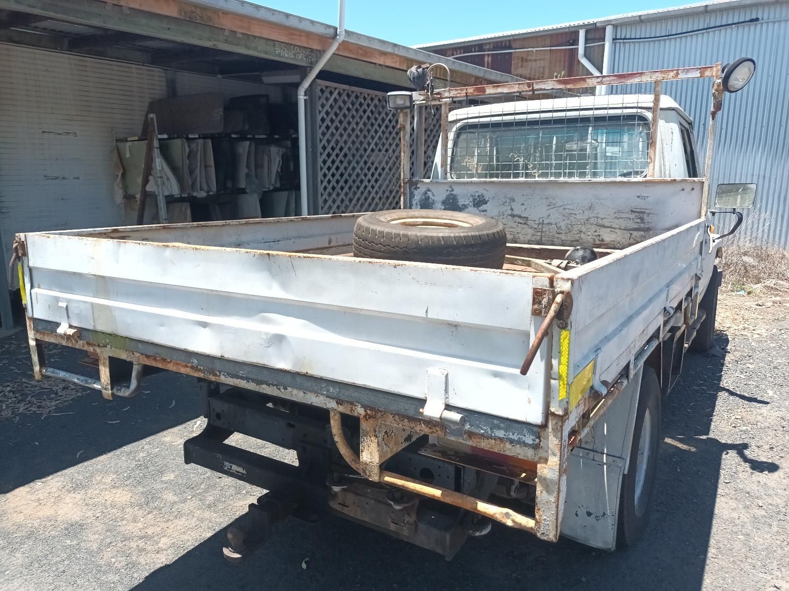 A White Truck with a Tire in the Bed is Parked in Front of a Building — South West 4WD Wreckers In Brisbane, QLD