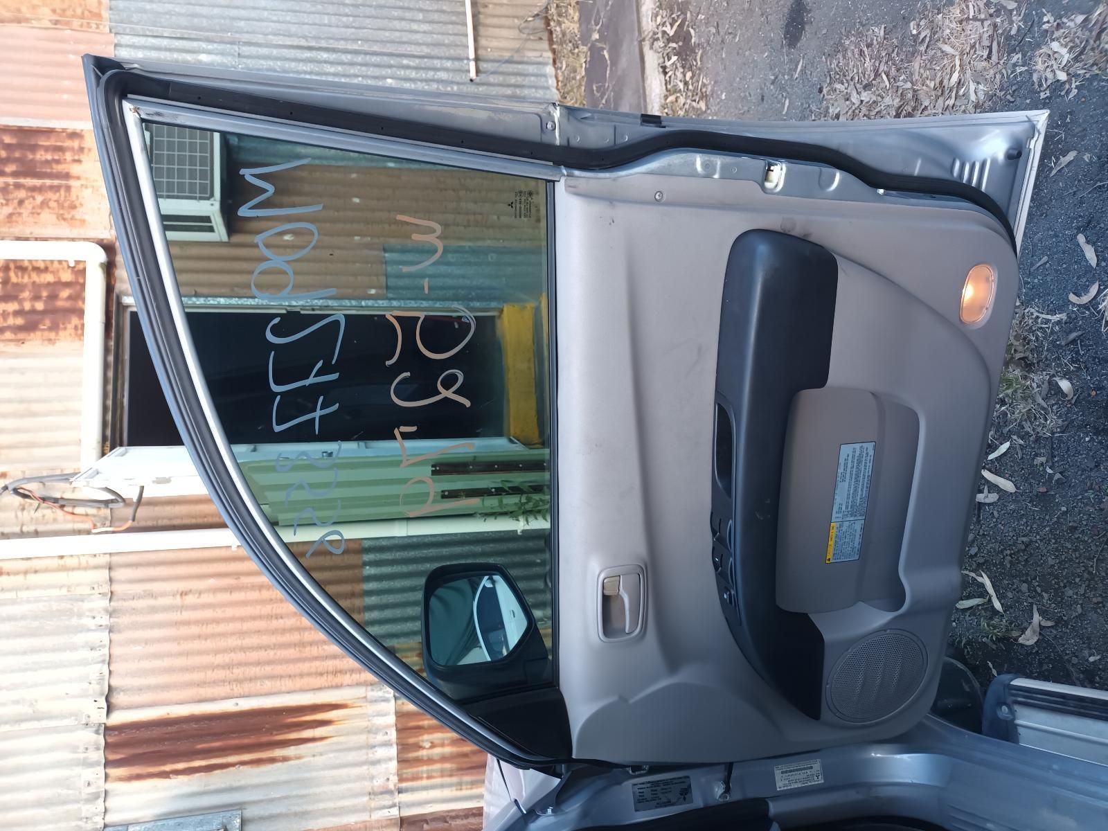 A Car is Parked in Front of a Rusty Building with the Door Open — South West 4WD Wreckers In Brisbane, QLD