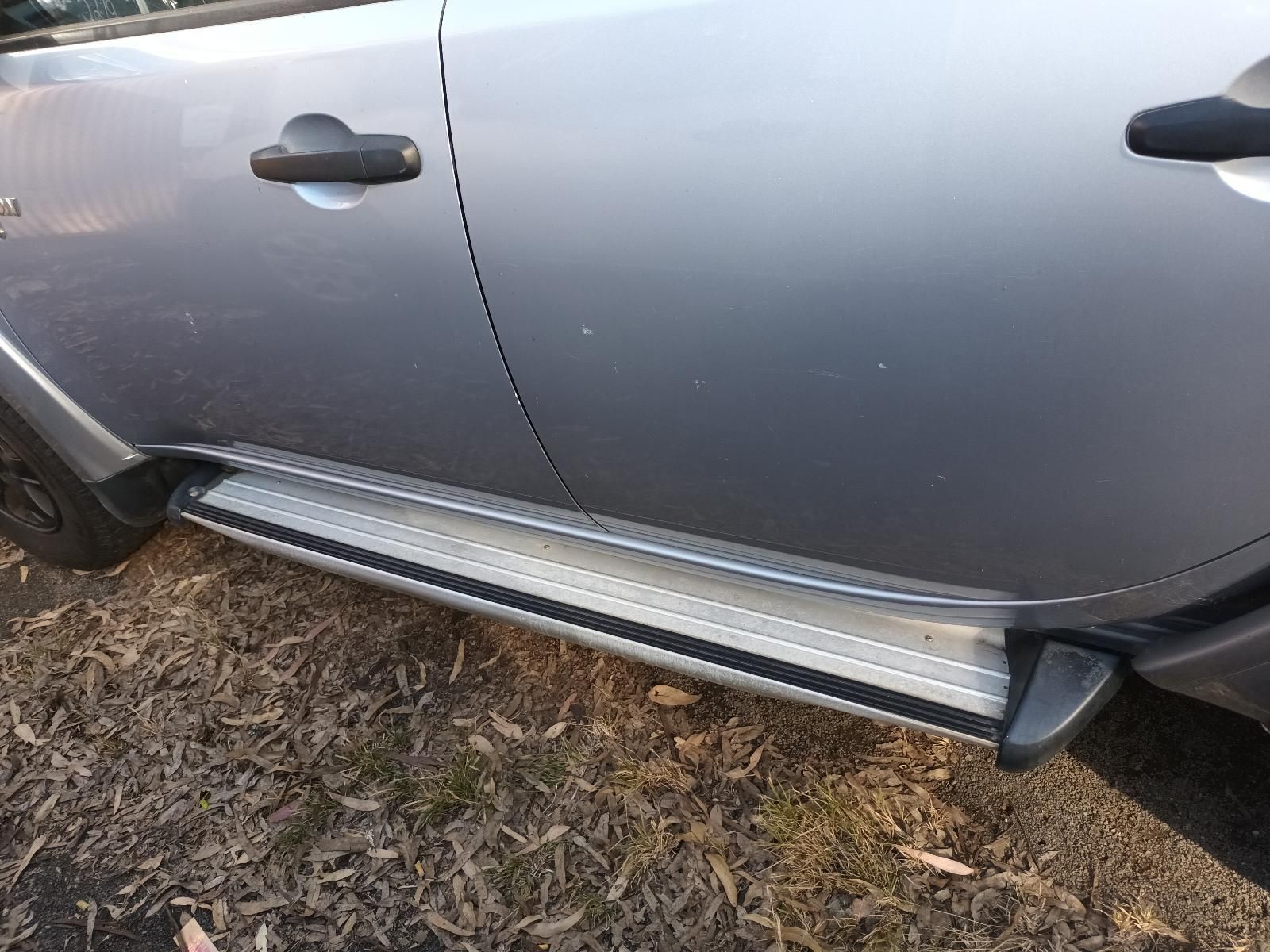 A Silver Car with a Side Step is Parked in the Grass — South West 4WD Wreckers In Brisbane, QLD