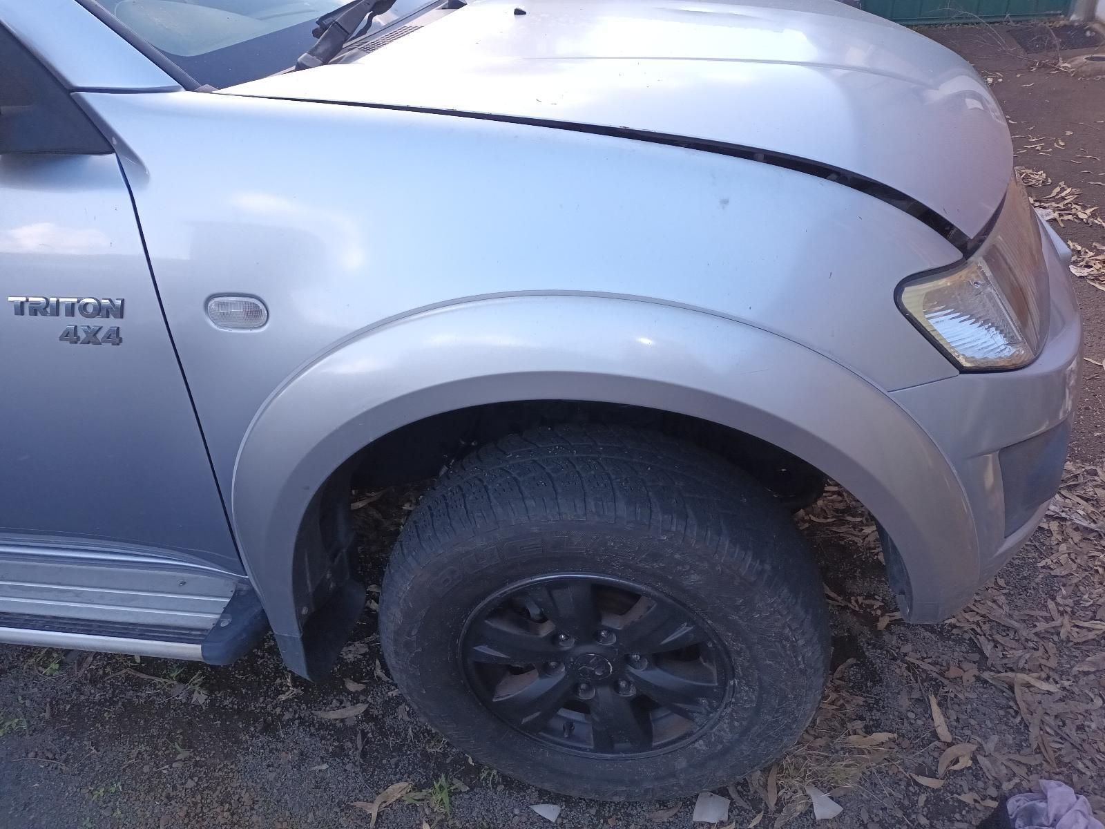 A Silver Truck with a Black Tire is Parked on the Side of the Road — South West 4WD Wreckers In Brisbane, QLD