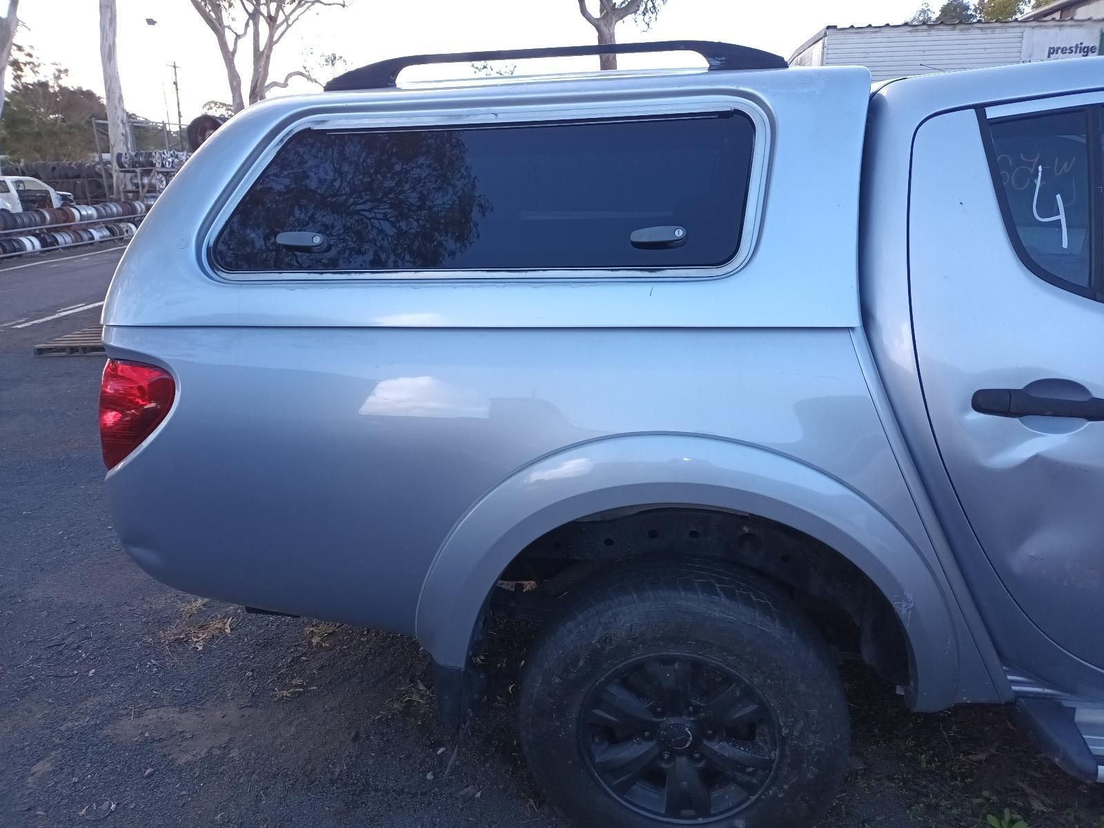 A Silver Truck with a Canopy on the Back is Parked on the Side of the Road — South West 4WD Wreckers In Brisbane, QLD