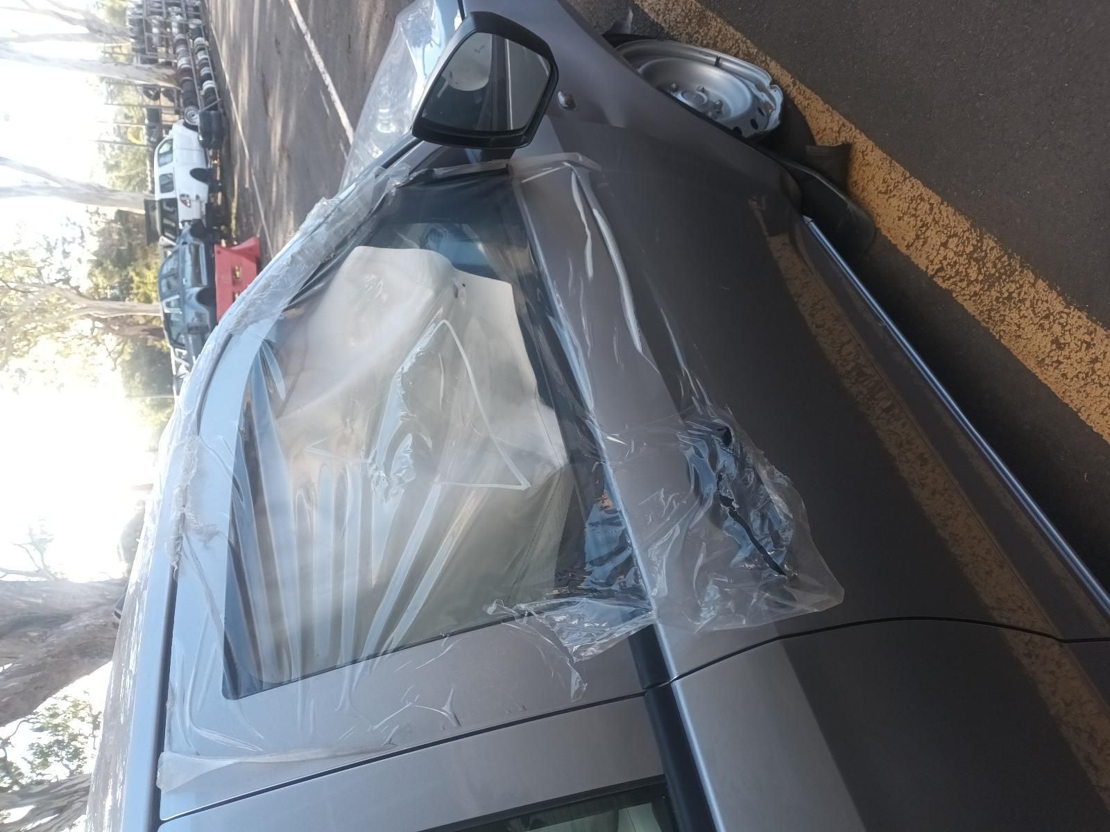 A Silver Car Wrapped in Plastic is Parked on the Side of the Road — South West 4WD Wreckers In Brisbane, QLD