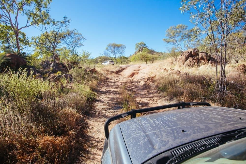 A Car is Driving Down a Dirt Road in the Desert — South West 4WD Wreckers In Harristown, QLD