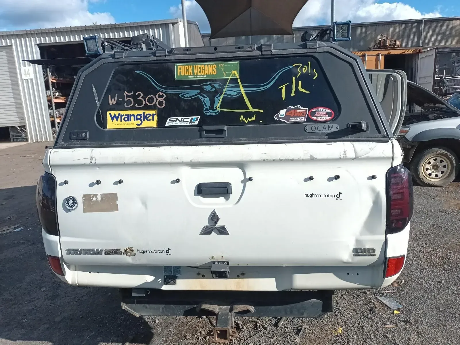 White Mitsubishi Truck Rear With a Canopy, Stickers, and a Trailer Hitch in a Lot — South West 4WD Wreckers In Brisbane, QLD