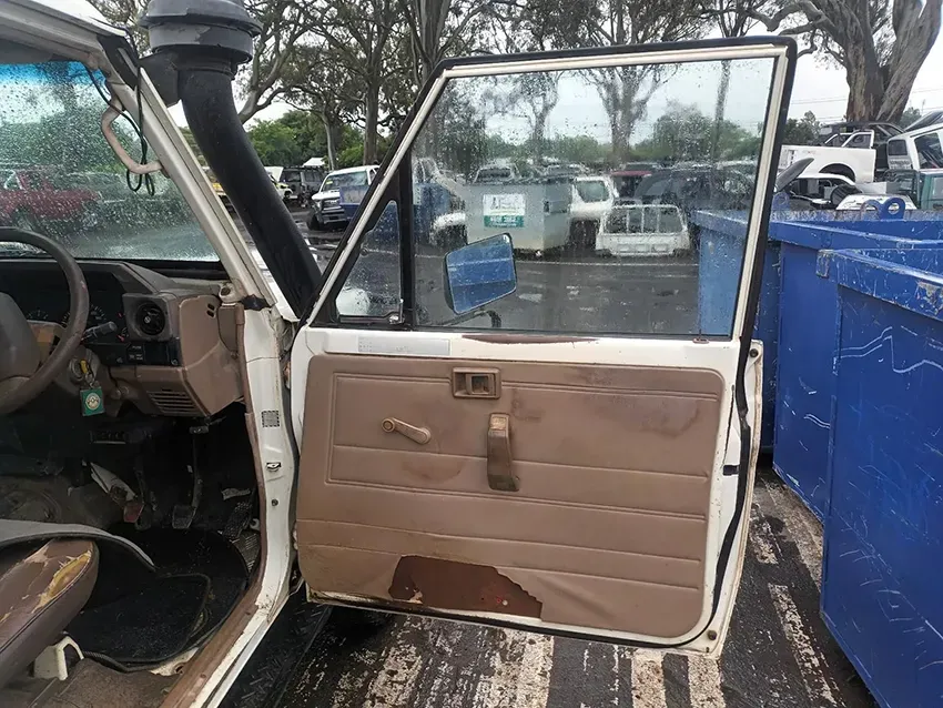 A White Car With the Door Open is Parked in a Parking Lot — South West 4WD Wreckers In Brisbane, QLD