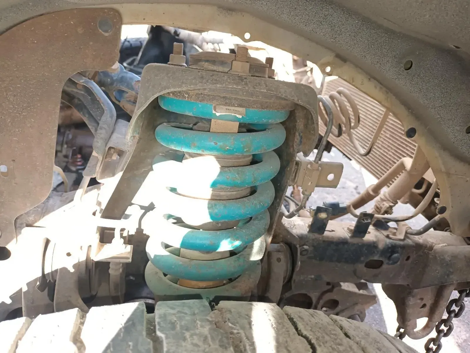 Blue Suspension Coil in a Vehicle's Wheel Well, Showing Rust and Wear — South West 4WD Wreckers In Brisbane, QLD