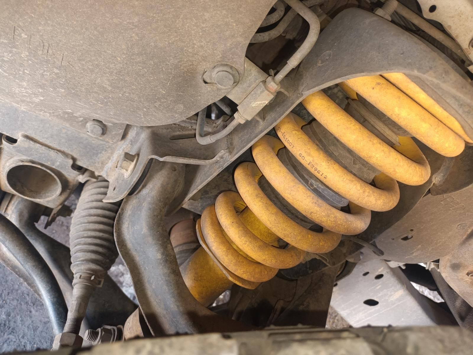 Close-Up of A Dusty Yellow Coil Spring and Suspension Under a Vehicle — South West 4WD Wreckers In Harristown, QLD
