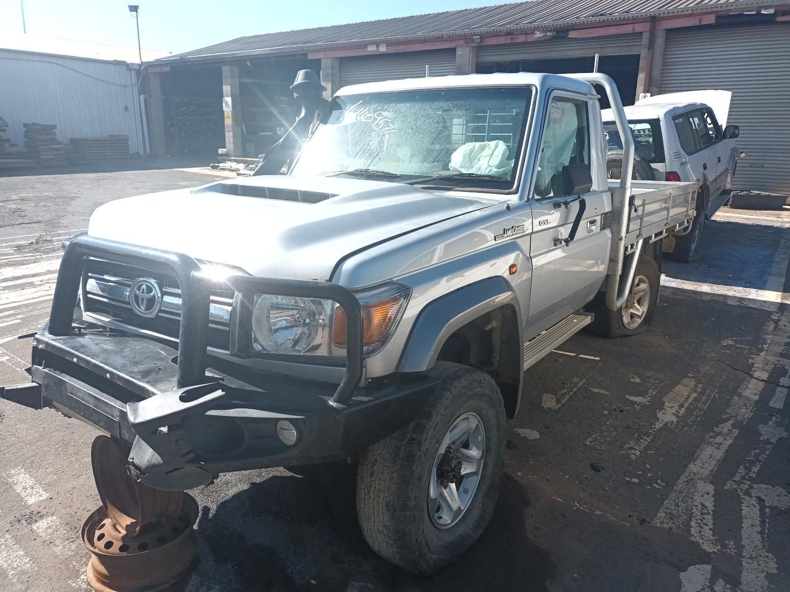 A Man is Standing Next to a Tow Truck With a Car on It — South West 4WD Wreckers In Brisbane, QLD