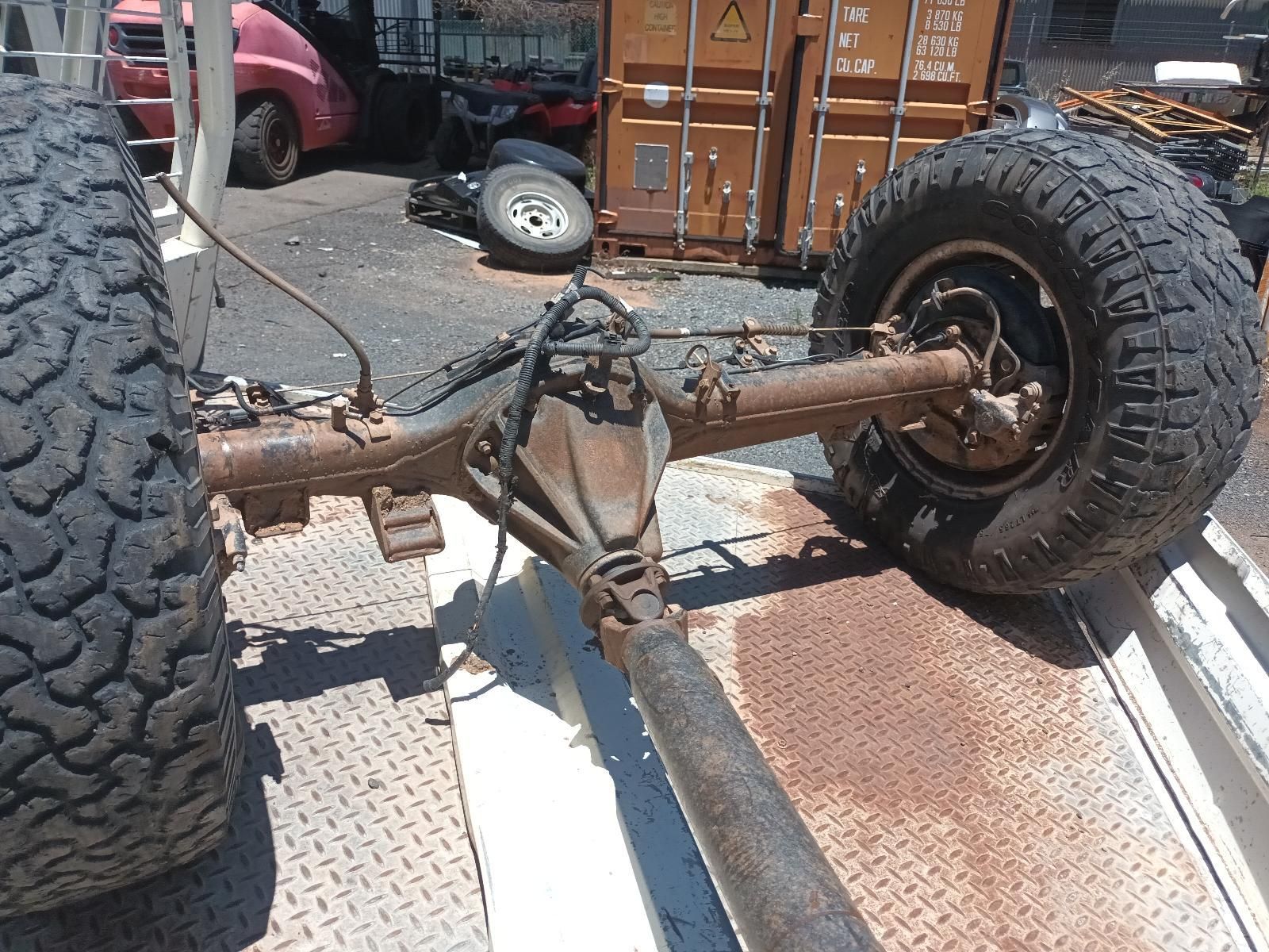 Rusty Off-Road Vehicle Axle and Large Tyres on A Trailer Bed, Viewed from Behind — South West 4WD Wreckers In Harristown, QLD