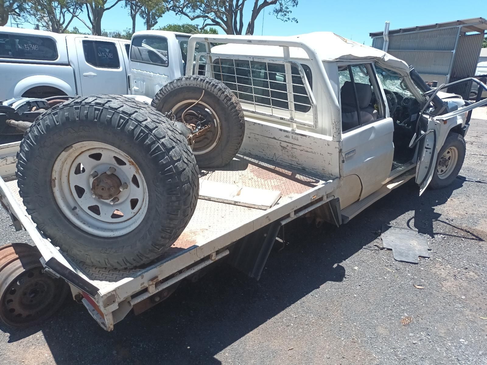 White Pickup Truck with Large Spare Tyres on A Flatbed Tow Truck — South West 4WD Wreckers In Harristown, QLD