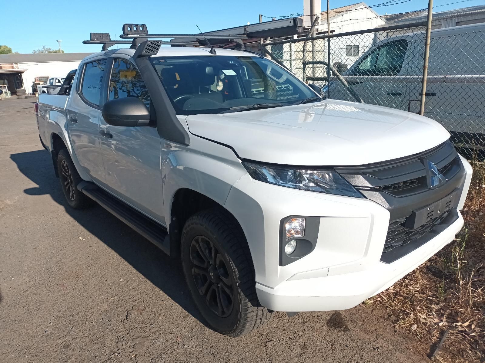 White Mitsubishi Triton Pickup Truck With a Snorkel and Roof Rack Parked Outdoors — South West 4WD Wreckers In Brisbane, QLD