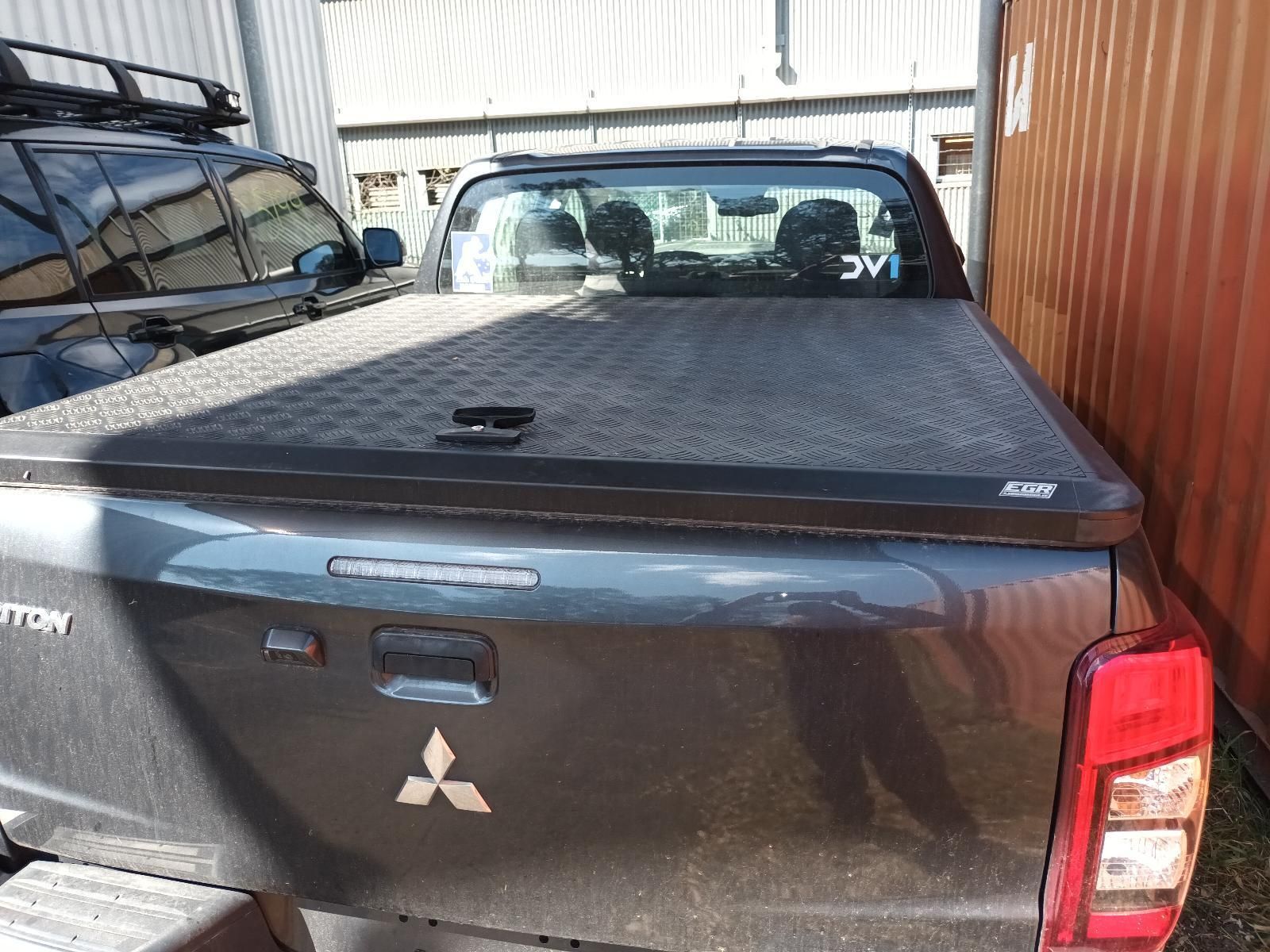A Black Truck with a Black Bed Cover is Parked Next to a Building — South West 4WD Wreckers In Brisbane, QLD