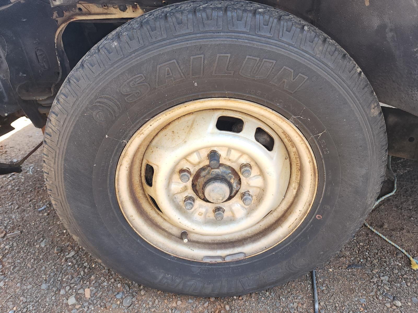 Dirty Car Tire on a Worn Steel Rim, Parked on Gravel — South West 4WD Wreckers In Harristown, QLD